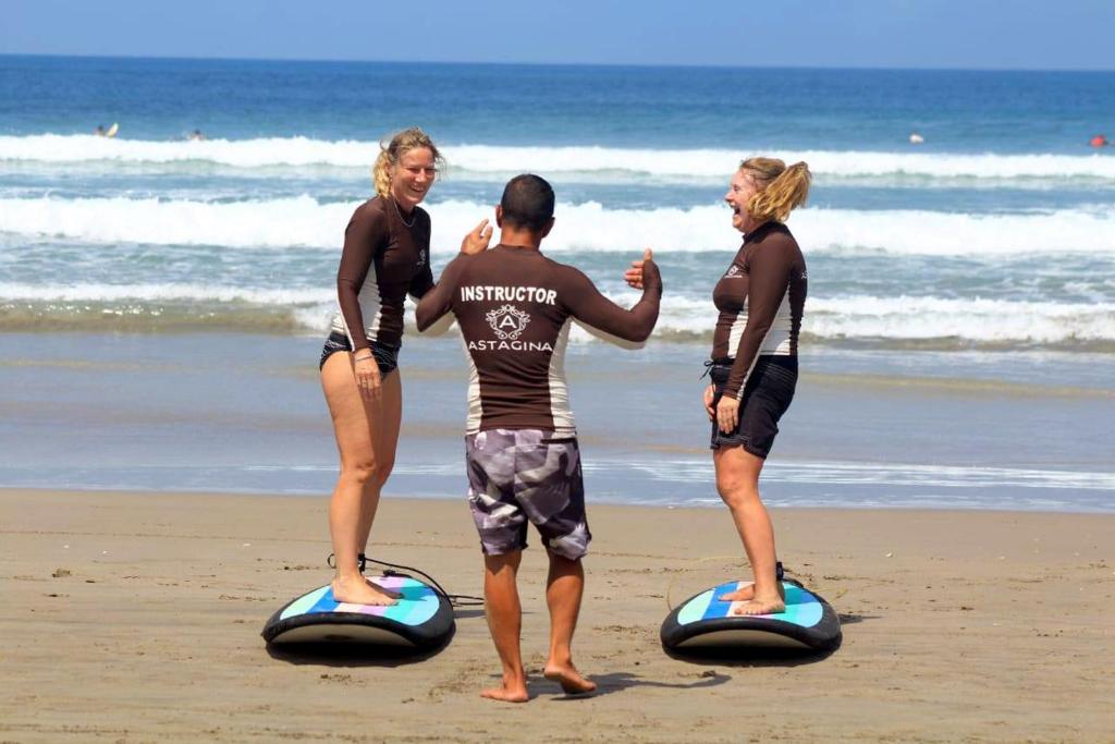 Surf lesson with instructor at Astagina Resort beach in Bali.