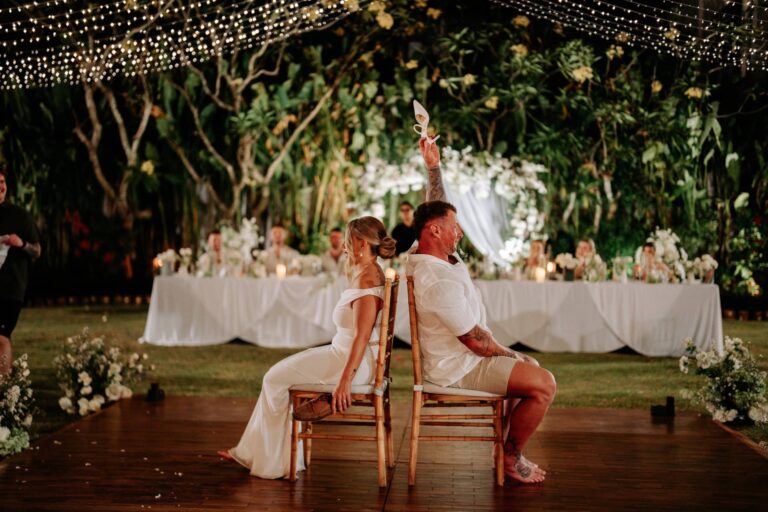 Evening garden wedding reception at Astagina Courtyard with fairy lights canopy, long dinner table setup, and couple playing wedding game during Bali garden wedding celebration at Astagina Resort Villa and Spa Legian