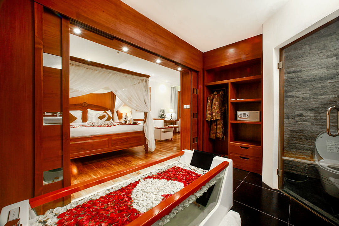 One Suite Room at Astagina Resort Bali with canopy bed, flower bathtub setup, and romantic ambiance