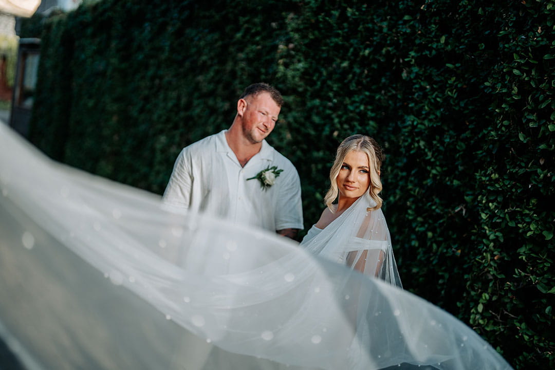 Romantic Bali garden wedding couple at Astagina Resort and Spa with flowing veil and lush green backdrop in Legian