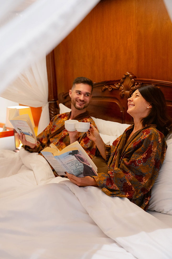 Couple enjoying a relaxing morning in bed at Astagina Resort Bali